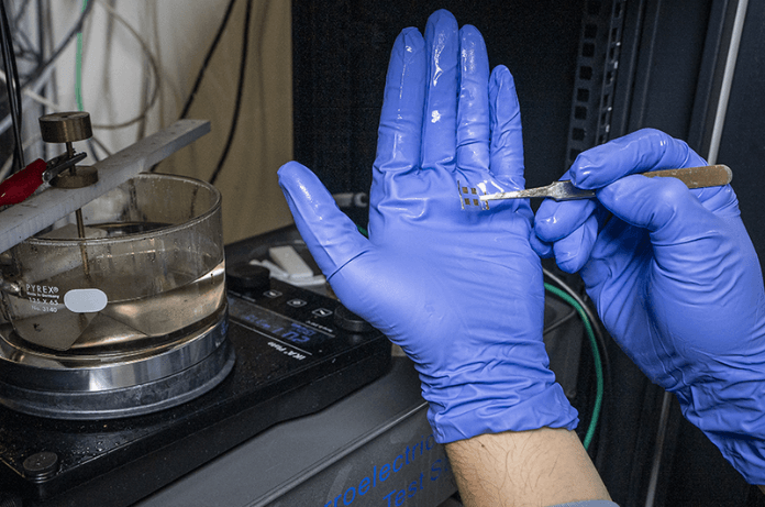 A researcher holds a fabricated thin-film capacitor